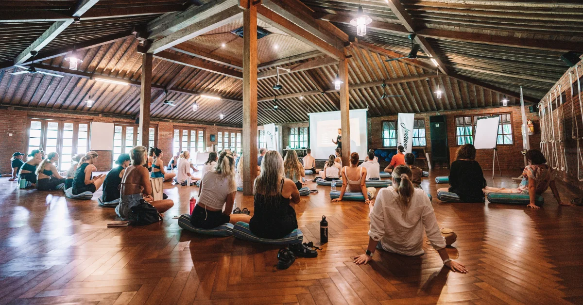 A serene yoga teacher guiding students in a sunlit studio, symbolizing the best online yoga teacher training programs for 2025